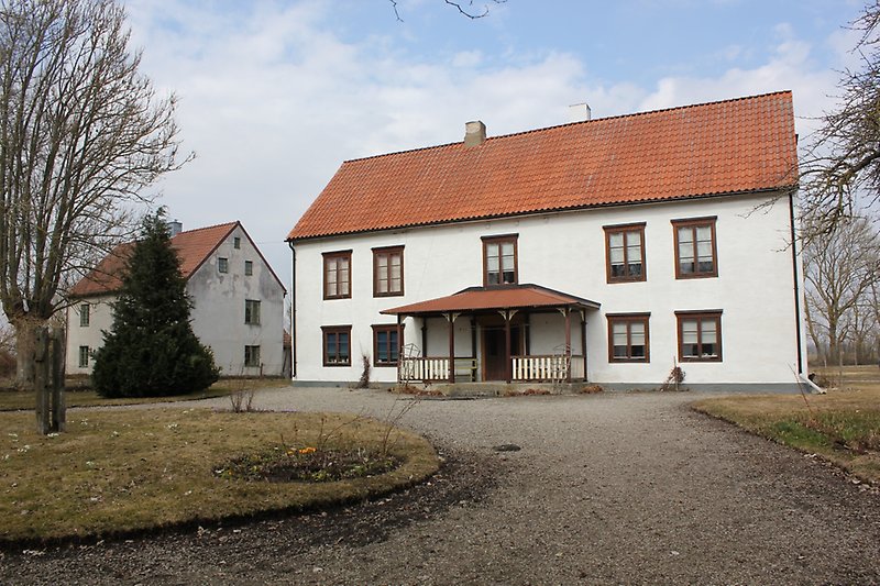 Ett vitt hus med en brun ytterdörr, bruna fönster och ett brunt tak.