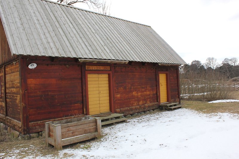 En röd trästuga, gula dörrar och ett trätak.