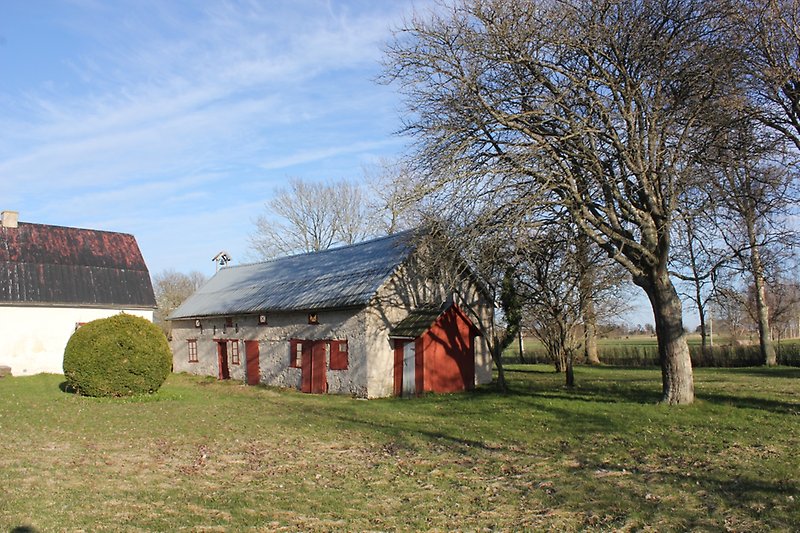 En vit byggnad med ett svart plåttak och en grå byggnad med ett silvrigt tak.