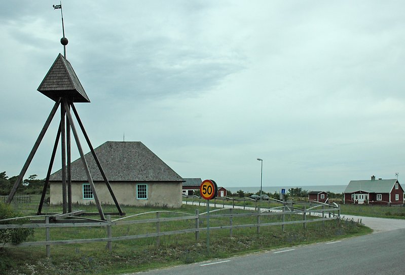 Ett envåningshus med putsade väggar, blåa fönster och havsutsikt.