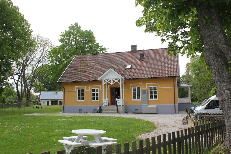 Ett orange hus med vita fönster och ett rött tegeltak med en skorsten.
