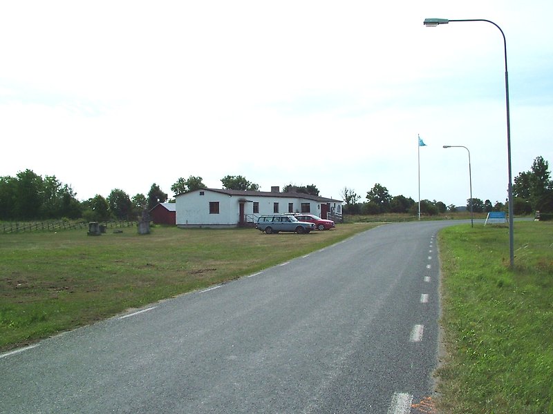 En vit envåningsbyggnad med röda dörrar, röda fönster och med två skorstenar på taket.