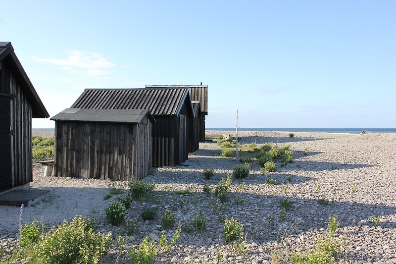 Flera träbodar är placerade i rad och ligger längs havet i Flerringe.