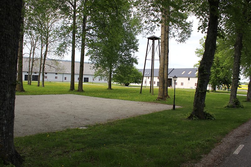En väldigt stor vit lada med svarta dörrar, små röda fönster och ett svart plåttak.
