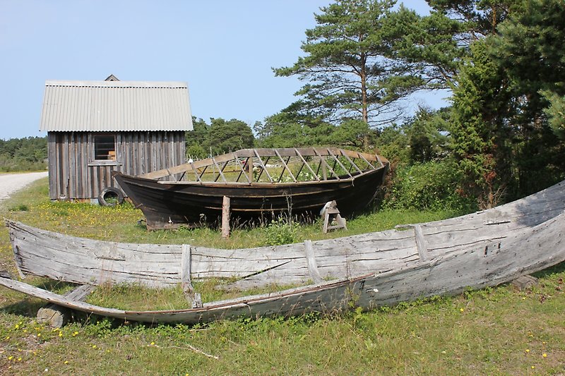 Bredvid en fiskebod pågår det en renovering av båtens skrov.