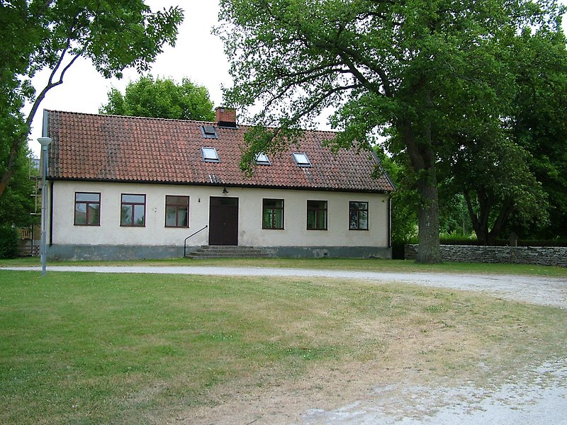 En envåningsbyggnad med bruna fönster, en brun ytterdörr och ett rött tegeltak med en skorsten.